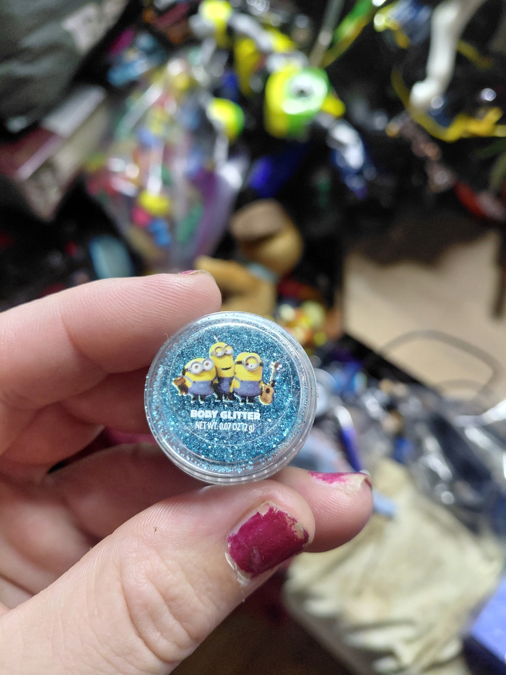 small, round container of blue-toned body glitter featuring Minions on lid .07oz